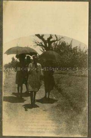 Afrikanischer Träger mit Frauen unter Sonnenschirmen