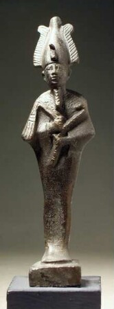 Ägyptische Osirisstatuette. "Statuette des Osiris m. Krummstab und Geißel. Hohe Krone Oberägy. m. zwei Flügel .... Das über dem Nacken ...(?) Gewand ist an seinem oberen Abschluß mit gestrichelten und punktierten Streifen verziert."