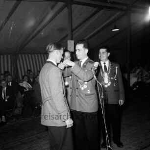 Schützenfest: Veranstalter Schützenverein Reinfeld und Umgebung von 1954 e.V.: Festplatz an der Ahrensböker Straße, im Festzelt: Königsproklamation: alter Jungschützenkönig Rolf Käselau überreicht neuem Jungschützenkönig Hermann Opitz Königskette: im Beisein von Vorsitzendem Eugen Richter und altem Schützenkönig Ulrich Wetzel: davor Mikrofon: hinten Gäste, 3. September 1960