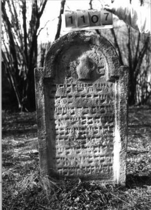 Grabstein 1107 (Index: 99753275) Material: Sandstein Zustand: verwitt/Textverlust Maße HxBxT: 113x66x9 cm Beschreibung: Stele, eingezog. Rundbogenabschluß, Schriftfeld eingetieft Symbolik: Levitenkanne: Grabstein 1107
