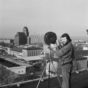 Fotograf der Deutschen Fotothek bei Stadtaufnahmen von erhöhtem Standort : Der Fotograf der Deutschen Fotothek, André Rous, auf dem Dach des Schwesternwohnheims beim Anfertigen von Stadtbildern. Blick nach Nordwesten gegen Hafenmühle (Dresdener Mühle am Alberthafen).