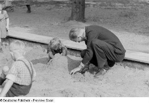 Ein Mann mit einem Kind, eine Sandburg bauend