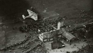 Flugplatz Dresden-Heller, Verkehrsflugzeug Junkers G 38 am Flugtag auf dem Rollfeld mit Zuschauern vor dem Abfertigungsgebäude mit Kontrollturm, Luftbild-Schrägaufnahme