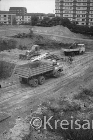 Schanzenbarg: Berufliche Schule des Kreises Stormarn: in Bau: Baugrube, Mann bei Vermessung, Bagger, Lkws, Bretter: hinten Hochhäuser, Wohnblocks