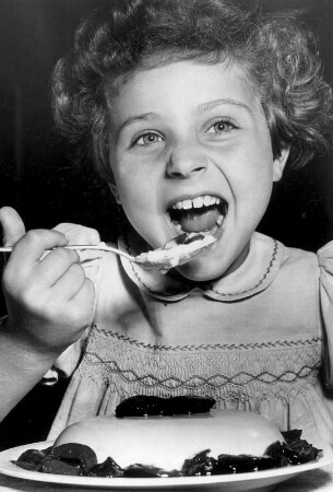 Ein Mädchen isst Pudding. Er scheint ihr zu schmecken