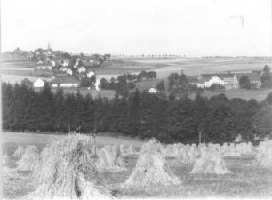 Berthelsdorf (Weißenborn-Berthelsdorf). Ortsteilansicht mit Pfarrkirche (1881/1883; G. L. Möckel) über ein Feld mit Getreidepuppen von Südost
