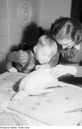Ein Junge schaut seiner Mutter beim Ausnehmen einer Gans zu