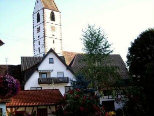Ansicht von Südwesten mit Kirche über Kirchhofmauer in erhöhter Lage am Ortsrand-Kirchturm mit Schießscharten für Armbrust sowie querliegenden Büchsenscharten