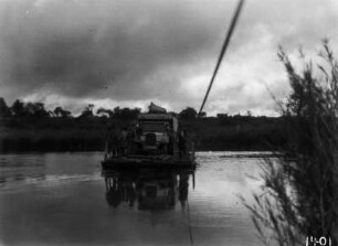 Überfahrt : Ein Lastkraftwagen der Expedition und einige Männer werden mit einer Fähre, die an einem Seil gezogen wird, über einen Fluss gebracht.