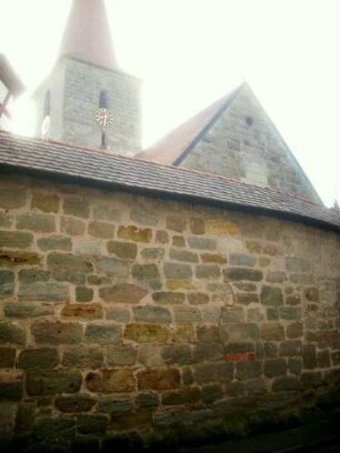 Ansicht von Westen mit Kirche (im Kern 15 Jh) über Kirchhofmauer (Wehrgang mit Steinbrüstung im 18 Jh abgetragen) von Ortsseite