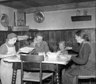 Arbeitmaid des Reichsarbeitsdienstes und Bauernfamilie beim Mittagessen