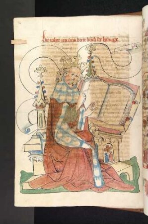 König am Pult deutet auf ein Buch