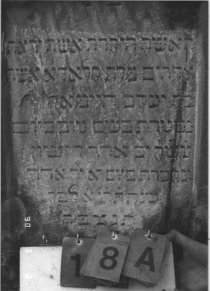 Grabstein 18 (Index: 99608702) Material: Sandstein Zustand: leicht verwittert Maße HxBxT: 115x55x12 cm Beschreibung: Stele auf Sockel, eingezogener Spitzgiebel mit Eckakroterien, vertiefter Textteil in gleicher Form mit Stalagtitengebälk: Grabstein 18A