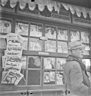 Mann vor einem ungarischen Kiosk mit deutschen Zeitungen