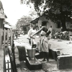 Lagos, Nigeria. Vorstadtsiedlung. Nigerianerinnen an einer öffentlichen Wasserentnahmestelle