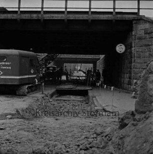 Pölitzer Weg: Bahnunterführung: Bau der Kanalisation: vorn zugeschüttete Baugrube: links Bagger: hinten Mitte Lkw, Arbeiter und Baumaterial: hinten rechts Fußgänger