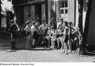Jungengruppe vor einer Jugendherberge beim Musizieren