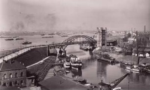 Duisburg-Ruhrort, Hafen : Duisburg-Ruhrort. Eisenbahn-Bassin mit Schleppzügen. Blick nach Nordwesten rheinabwärts. Straßenbrücke über die Hafeneinfahrt