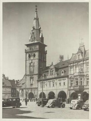Komotau (heute Chomutov). Blick über den Marktplatz zur von 1518 bis 1539 errichteten spätgotischen Dekanalkirche Mariä Himmelfahrt. Auf dem Markzplatz sind Personenkraftwagen abgestellt.