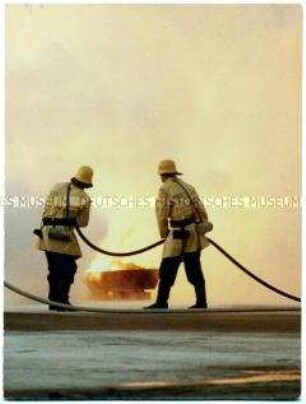 Zwei Feuerwehrmänner löschen einen Brand (Altersgruppe 18-21)