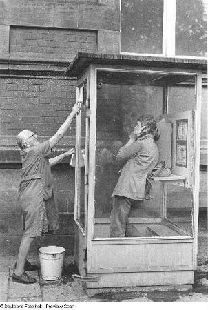 Jana Richter in einer Telefonzelle und alte Frau beim Saubermachen dieser Telefonzelle, aufgenommen in Gotha