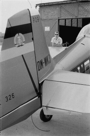 Riesa. Ein Mann unterhält sich mit dem verdeckt neben einem Flugzeug stehenden Fluglehrer Wolfgang Winkler
