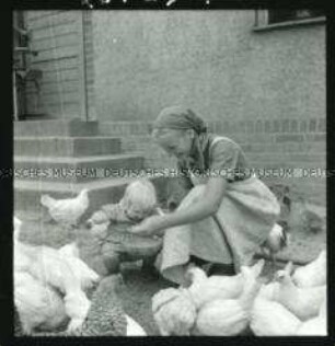 Arbeitsmaid des Reichsarbeitsdienstes mit Kind beim Hühnerfüttern