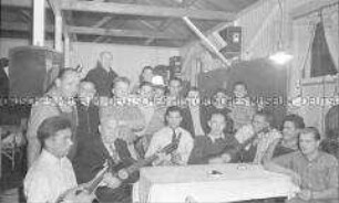 Selbstversenkung des Hochseepassagierdampfers "Columbus" am 19. Dezember 1939, Besatzungsangehörige im Internierungslager auf Angel Island, Kalifornien, teilweise mit Instrumenten um einen Tisch gruppiert