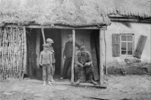Zweiter Weltkrieg. Zur Einquartierung. Sowjetunion. Angehöriger der deutschen Wehrmacht mit Einheimischen vor einer Bauernhütte