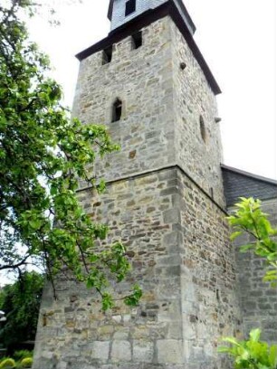 Dissen-Evangelische Kirche - Kirchturm von Südwesten (beachte sehr unterschiedlichen Mauersteinverband) mit vermauerten Zinnen im Obergeschoß unter der Glockenstube sowie Pechnasen im Süden