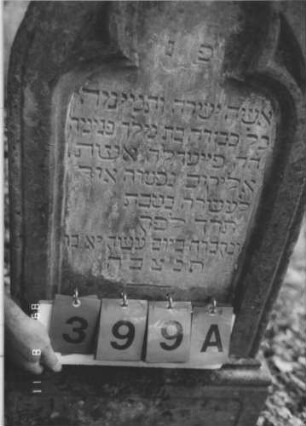 Grabstein 399 (Index: 99799632) Material: Sandstein Zustand: verwittert, Farbreste in den Lettern, Mittelaufsatz fehlt Maße HxBxT: 122x46x14 cm Beschreibung: Stele, Abschluß Eselsrücken, Mittelaufsatz fehlt, Schriftfeld eingetieft in Maßwerkform, Sockel: Grabstein 399A