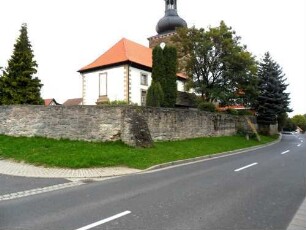 Evangelische Pfarrkirche - Ansicht von Südwesten mit Kirche über Kirchhofmauer (Wehrgang mit Brüstung und Schießscharten abgetragen) in übersichtlichem Verlauf