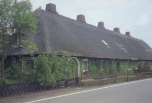 Neufresenburg: ehemalige Gutsarbeiterkate: traufständige Mehrfamilienkate aus Backstein mit Reetdach: Straßenfront, Giebelseite