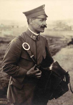 Mann seitlich stehend in Uniform. Briefträger mit lederner Umhängetasche. Halbnahe