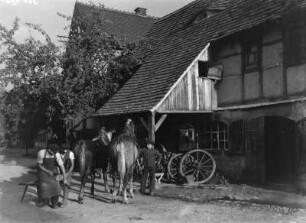 Dorfschmiede : Hufschmiede beim Beschlagen der Hufe vor der Schmiede