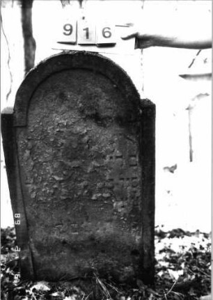 Grabstein 916 (Index: 99753213) Material: Sandstein Zustand: abgeblätt/verwitt/fast völl. Textverlust Maße HxBxT: 116x67x16 cm Beschreibung: Stele, eingezogener Rundbogenabschluß, Schriftfeld eingetieft: Grabstein 916