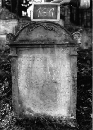 Grabstein 151 (Index: 100090449) Material: Sandstein Zustand: abgeblättert/verwittert mit Textverlust Maße HxBxT: 90x62x11 cm Beschreibung: Segmentbogenabschluß mit runden Eckakroteren, rechteckiges Schriftfeld eingetieft Symbolik: gekreuzte Äste: Grabstein 151