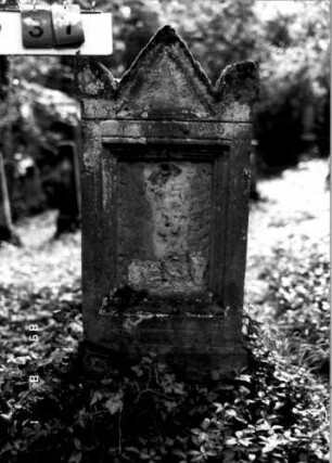 Grabstein 37 (Index: 100109260) Material: Sandstein Zustand: stark verwittert Maße HxBxT: 120x48x14 cm Beschreibung: Stele, Sockel rustica, giebelartiger Abschluß mit Eckakroteren, Schriftfeld rechteckig: Grabstein 37