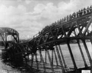 Deutsche Truppen überqueren eine gesprengte Eisenbahnbrücke bei Riga