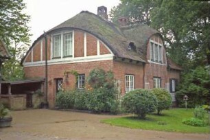 Trittauer Straße 45: Villa mit Reetdach: links Giebelseite mit Segmentgiebel, Fachwerk, Gartentür, Anbau für Brennholz: rückwärtige Traufseite, Mittelrisalit mit Segmentgiebel