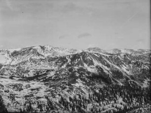 Bergpanorama : Eine Berglandschaft mit verschneiten Gebirgszügen im Hintergrund. Im Vordergrund sitzen drei Mitglieder des Transkontinentalen Geographenkongresses