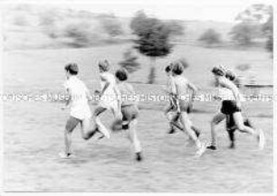 Sieben Jungen in Sportkleidung rennen auf einer Wiese (Altersgruppe bis 14)