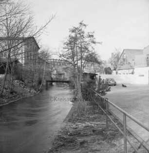 Trave: Stadtarm: rechts Parkfläche mit Pkw: links ehemaliges Fabrikgebäude Richtung Schultwiete: hinten Fußgängerbrücke