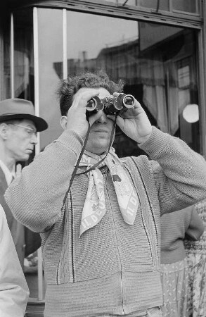Ein Mann mit einem Fernglas und einem Halstuch mit der Aufschrift "II. Deutsches Turn- und Sportfest"