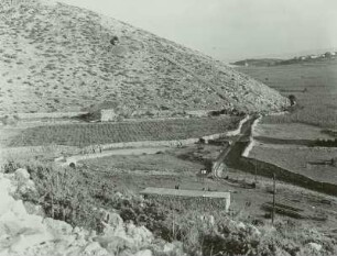 Kroatien, Insel Rab, von Mauern umgebene Maisfelder vor verkarstetem Hügel sowie Schienenstrang einer Feldbahn