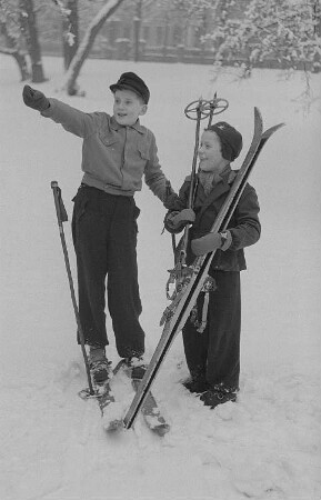 Kinder beim Ski- und Schlittenfahren, zwei Jungen mit Skiern nach der Abfahrt
