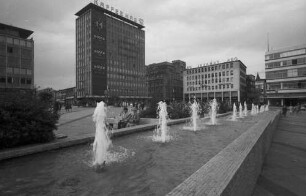 Essen: Gildenplatz [Kennedyplatz], Reihe von Springbrunnen im Vordergrund