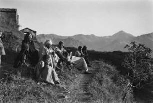 Männer der Kabylen : Eine Gruppe Männer der Kabylen sitzt vor dem Dorf, vor ihnen ein Feigenbaum.