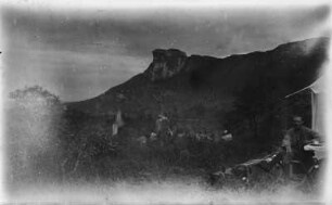 Lager am Berg : Blick auf die felsige Landschaft. Am rechten Bildrand sitzt vermutlich Hans Meyer vor seinem Zelt an einem Tisch