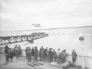 Ein Gruppe von Passagieren an Bord des Hochseepassagierdampfers "Bremen" beobachtet das Herannahen des Katapultflugzeugs HE 12 D-1717